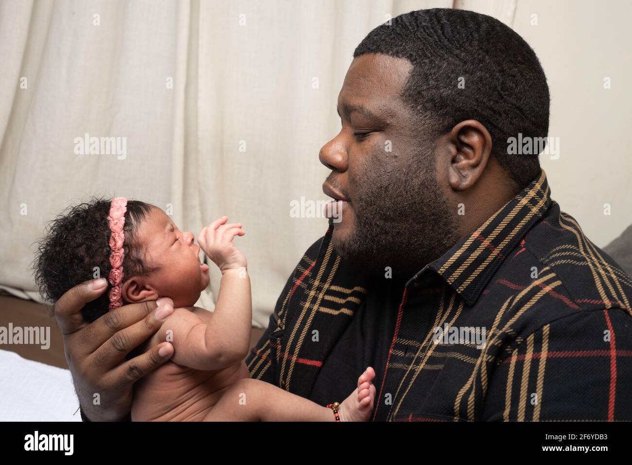 Newborn baby girl 3 weeks old, held by father, crying, talked to Stock Photo