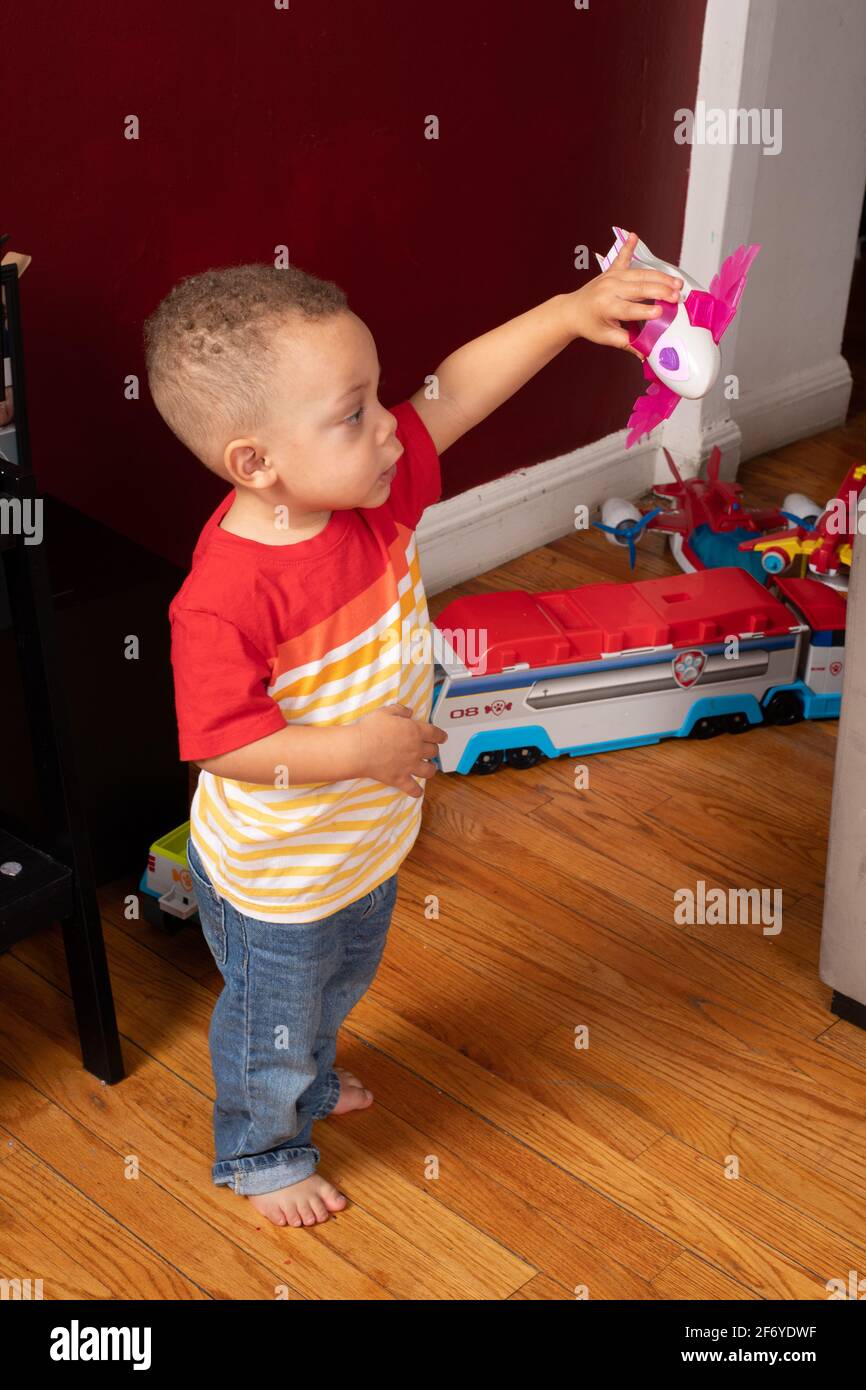 2 year old boy playing with toy vehicles, holding toy airplane, making it fly and making sounds Stock Photo
