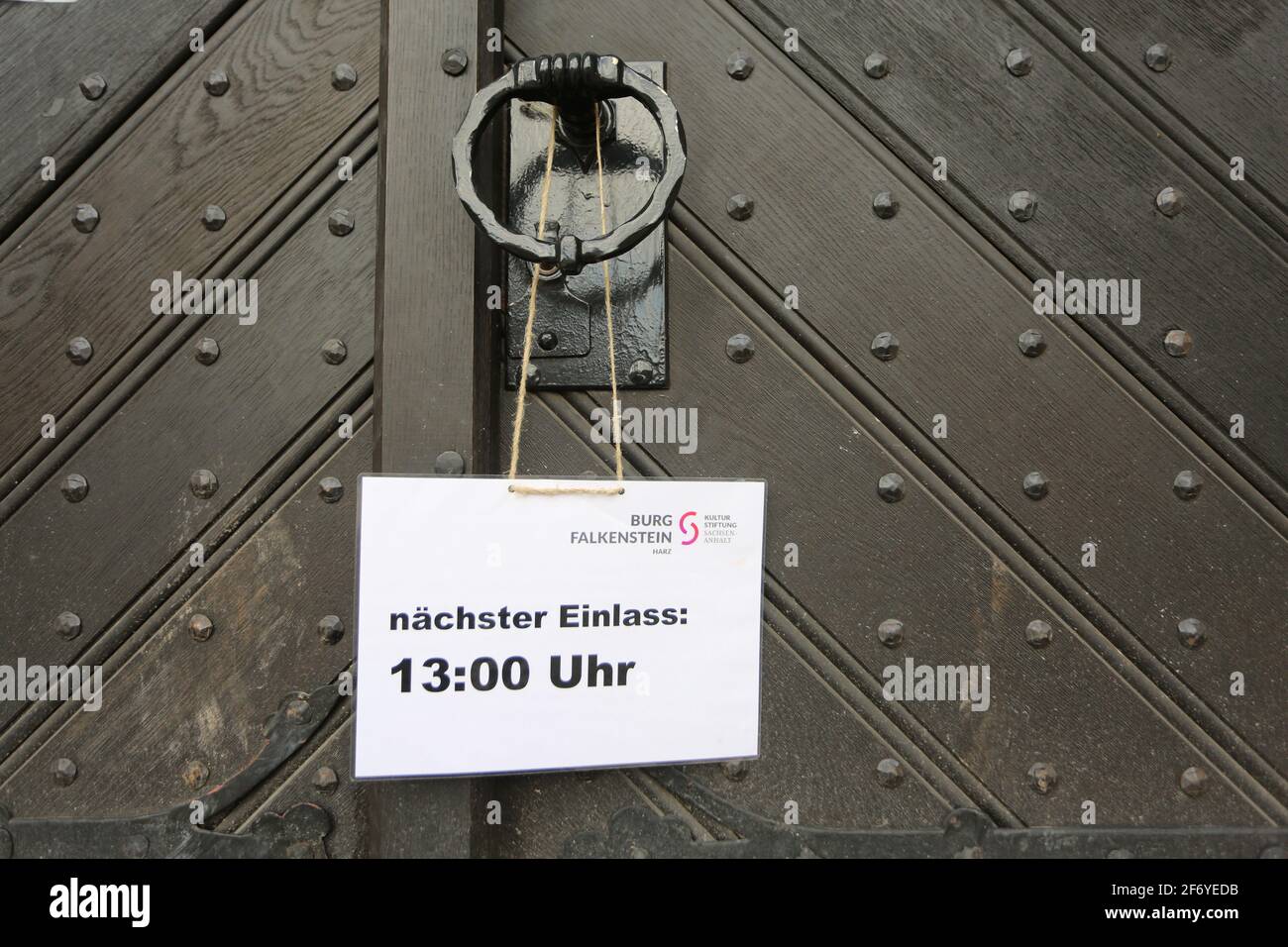 03 April 2021, Saxony-Anhalt, Pansfelde: 'Next admission 1 p.m.' is written on a sign hanging at the castle gate. Falkenstein Castle in the southern Harz region is open to visitors again for the first time after a long break due to the Corona pandemic. After booking by phone, visitors can tour the castle grounds as well as experience a falconry demonstration. The castle is located above the Selketal. The fortified complex was built at the beginning of the 12th century and passed as a fiefdom to the noble Asseburg family in the 15th century. Photo: Matthias Bein/dpa-Zentralbild/dpa Stock Photo