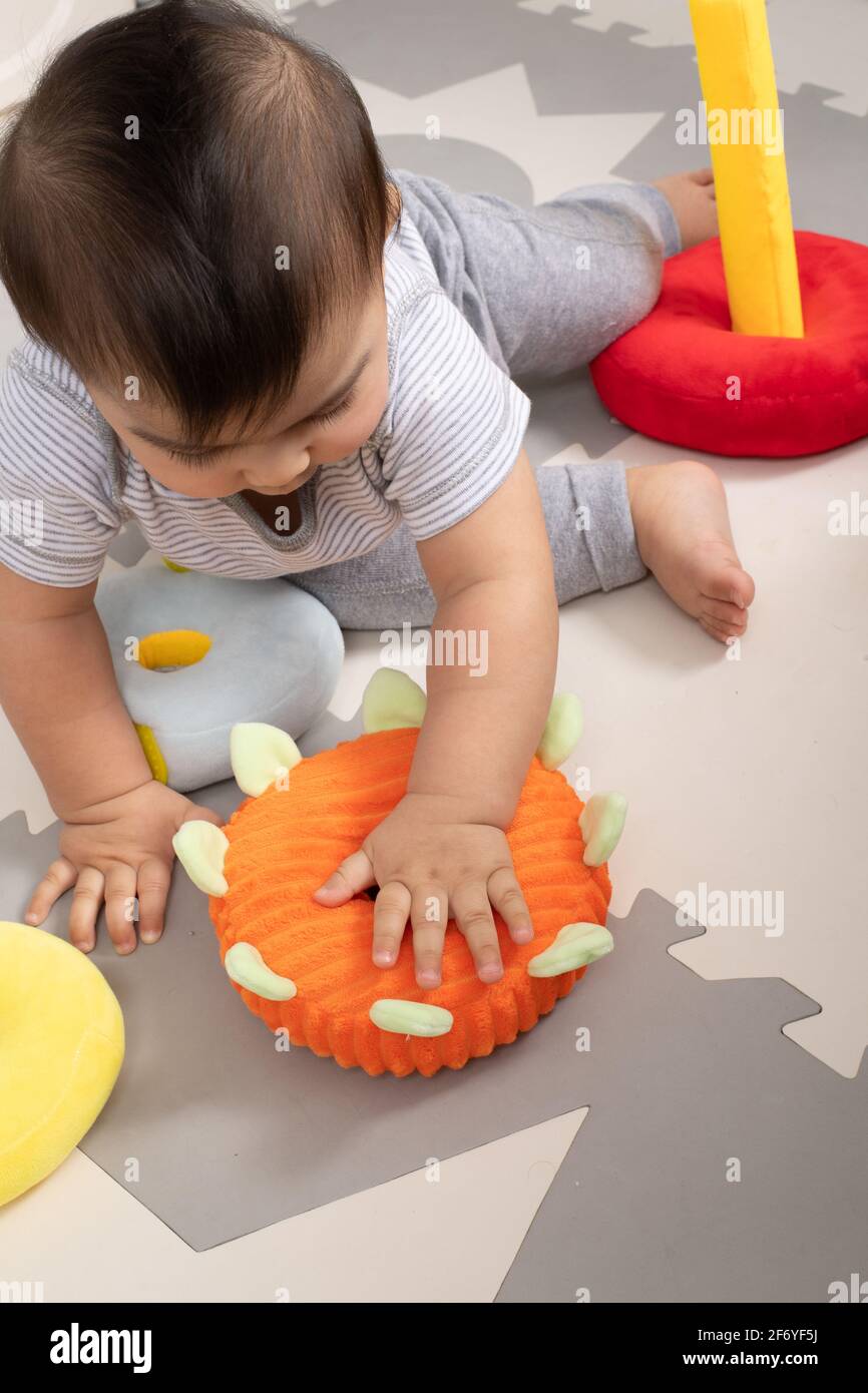 8 month old baby boy sitting playing with cloth rings toy Stock Photo