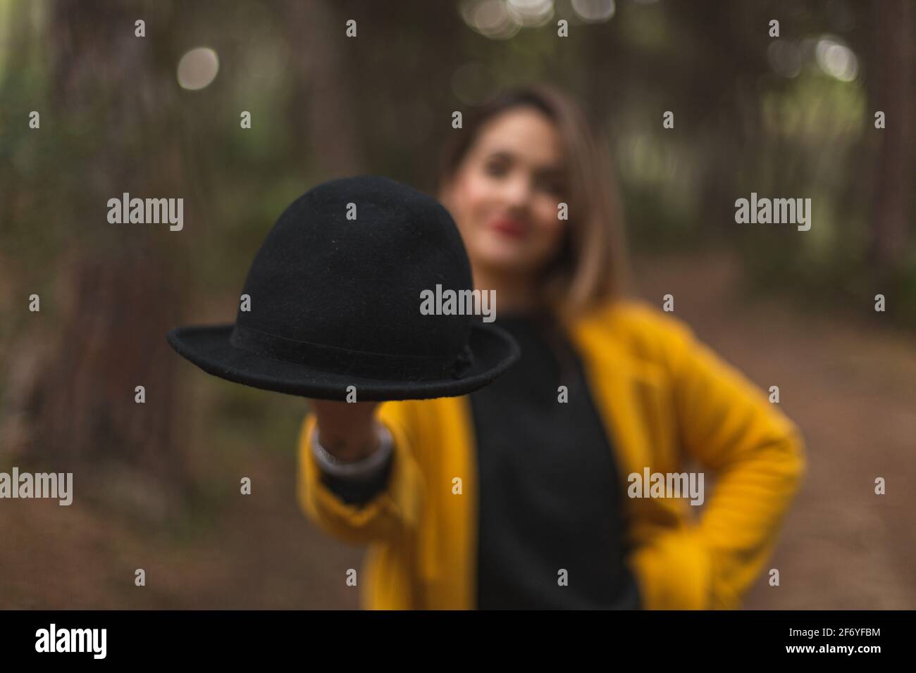 Woman in a yellow coat and hat in hand. Selective focus. Casual fashion. Stock Photo