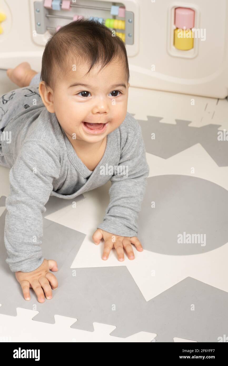 Six month old baby boy portrait smiling looking up to side on stomach pushing up with hands Stock Photo