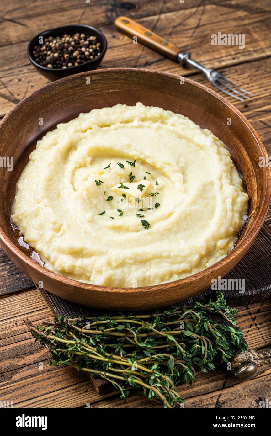 Mashed potatoes, boiled puree in a wooden plate. Wooden background. Top view Stock Photo
