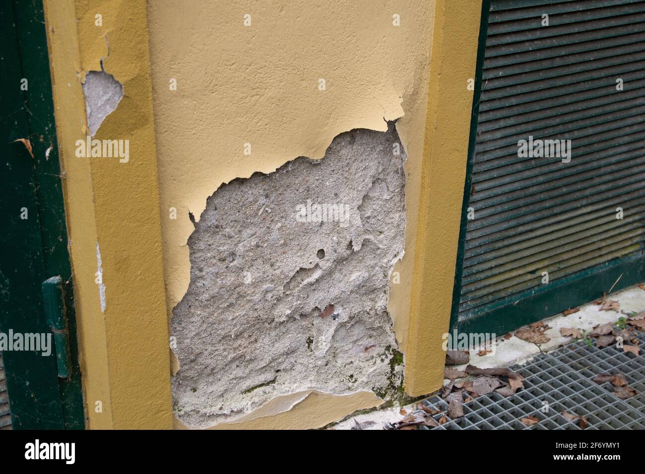Kaputte Fassade, abbröckelnder Putz auf gelber Mauer Stock Photo
