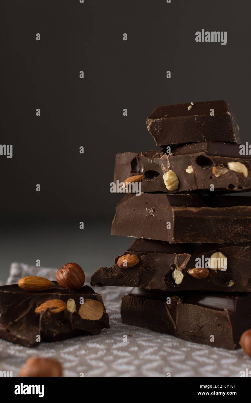 Dark chocolate with almonds and hazelnuts in a stack on brown background Stock Photo