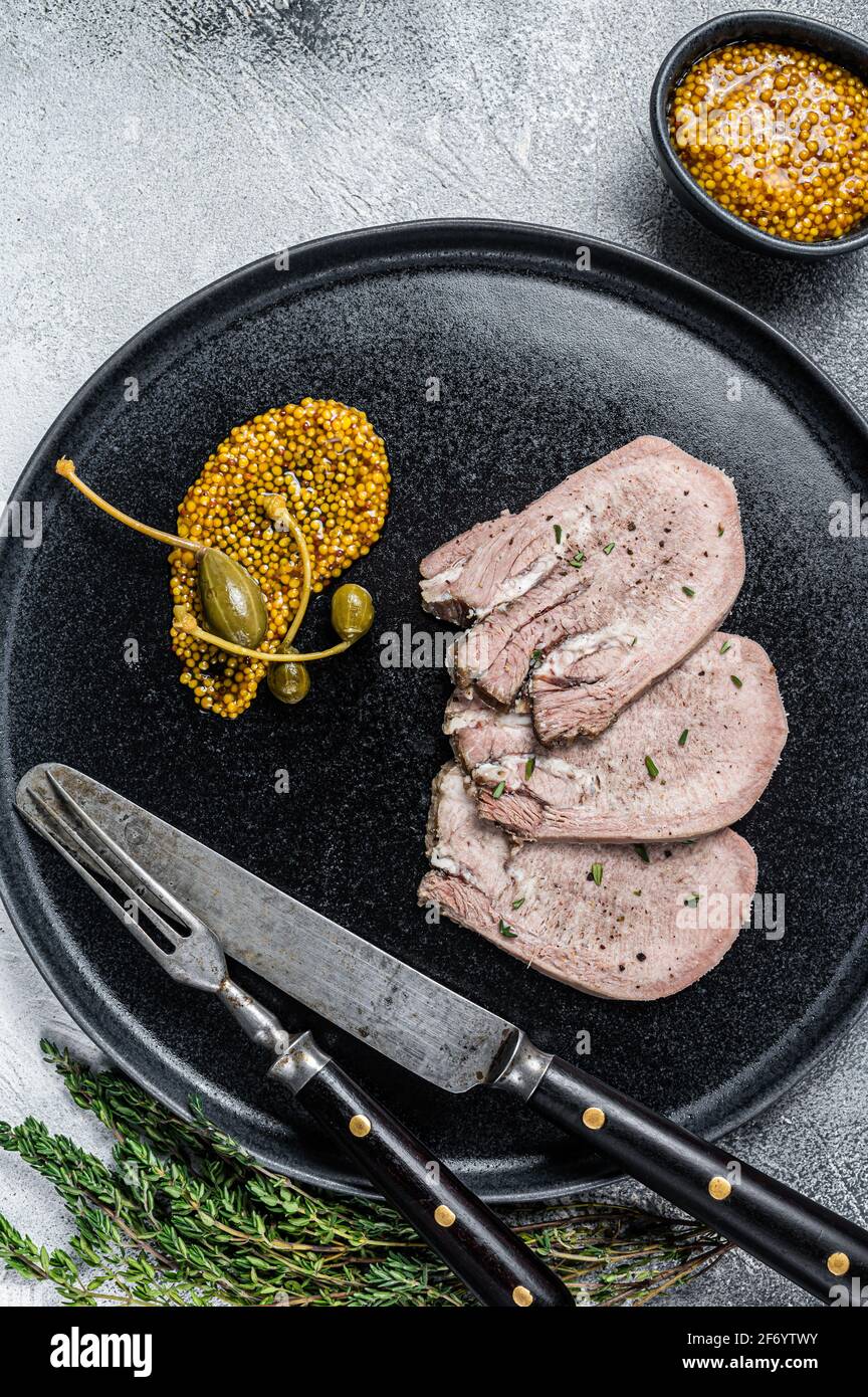 Veal or beef boiled tongue slices on a plate. White background. Top