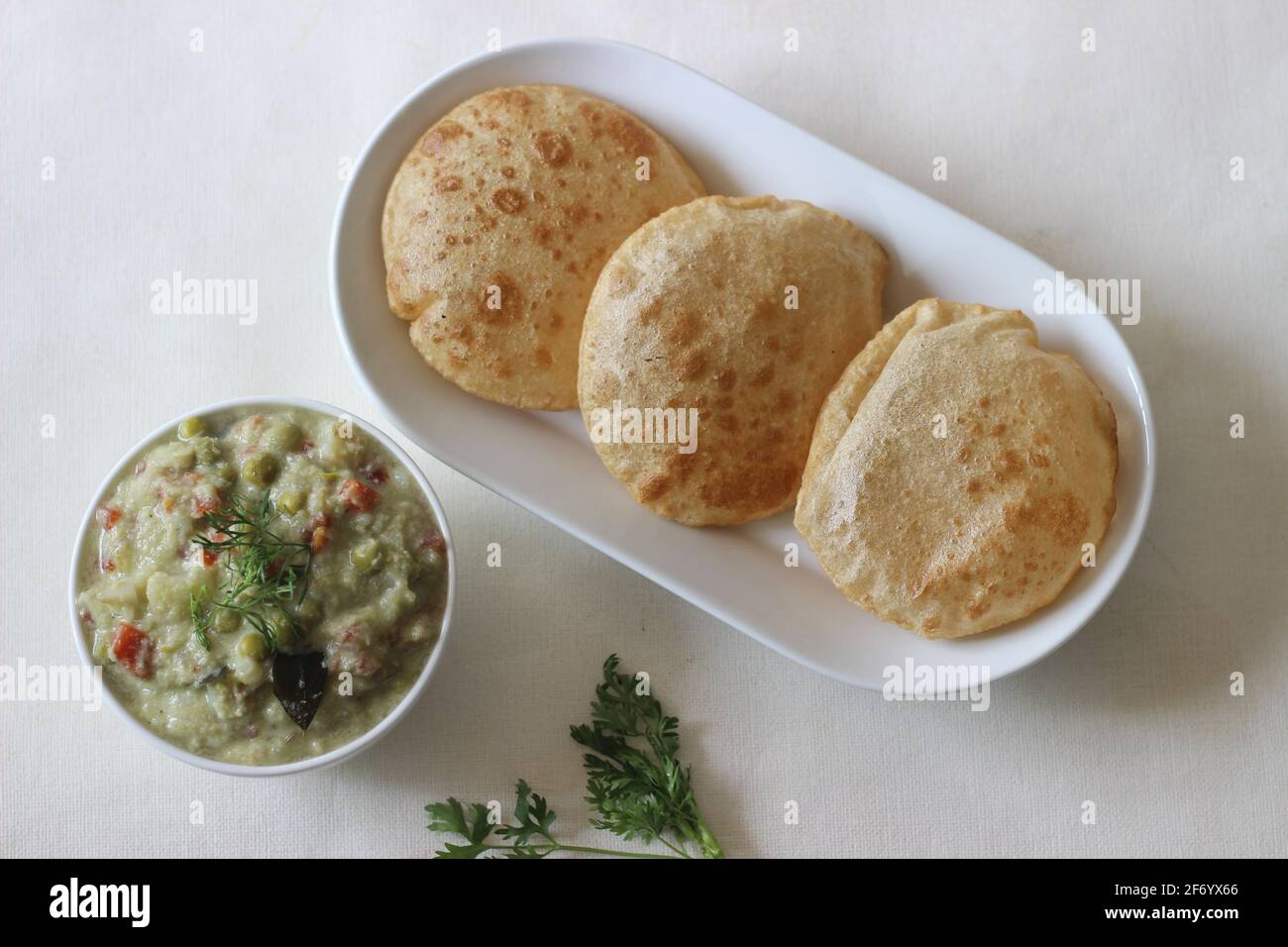 Deep fried indian flat bread served with mixed vegetable curry in a
