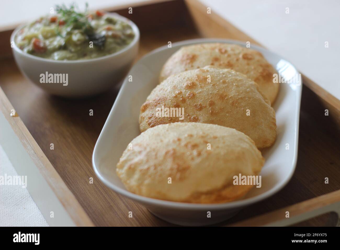 Deep fried indian flat bread served with mixed vegetable curry in a