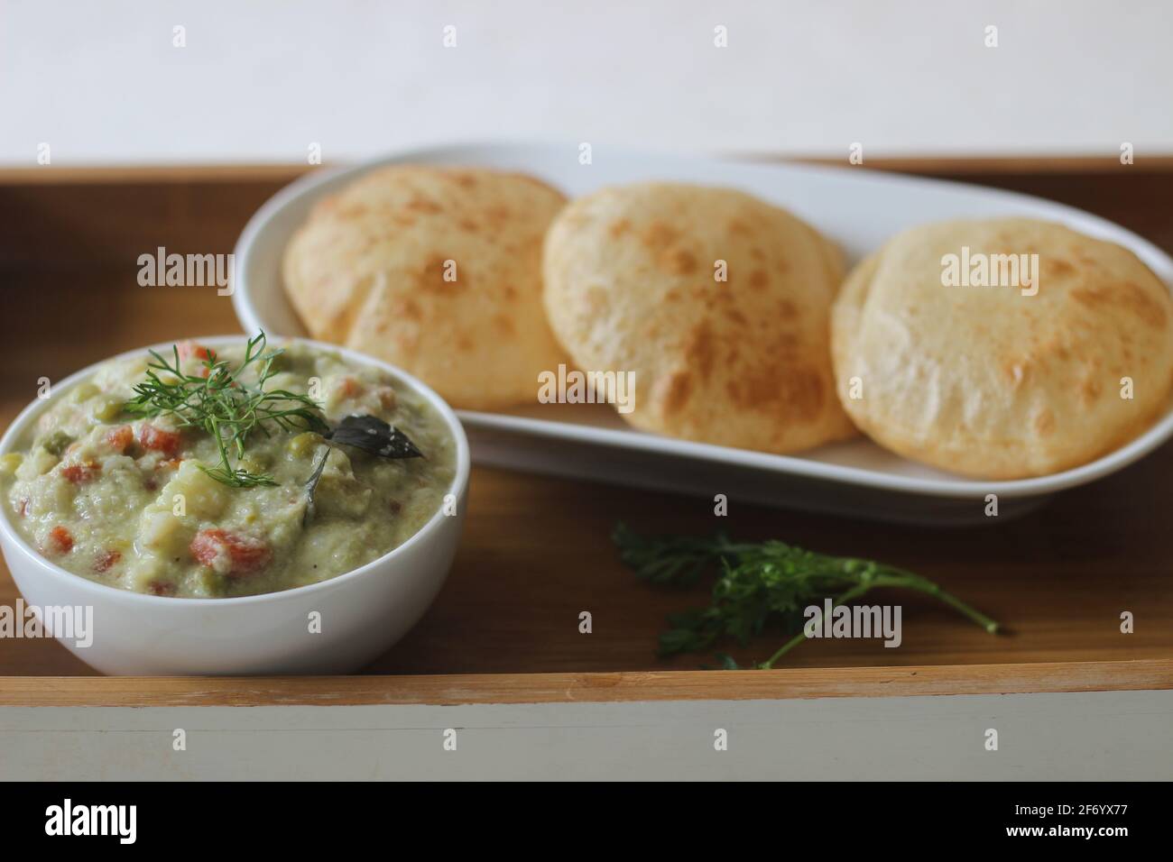 Deep fried indian flat bread served with mixed vegetable curry in a