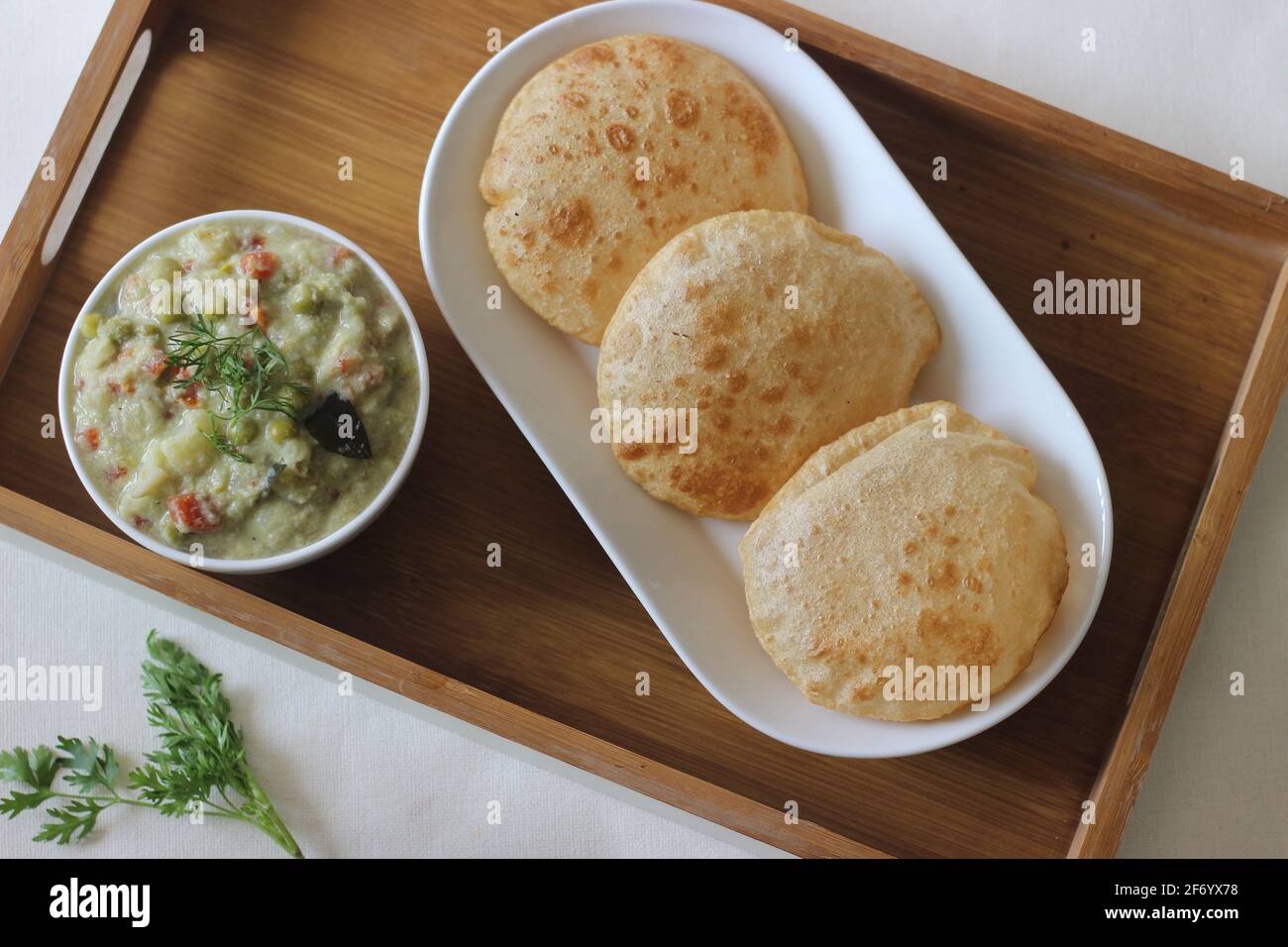 Deep fried indian flat bread served with mixed vegetable curry in a
