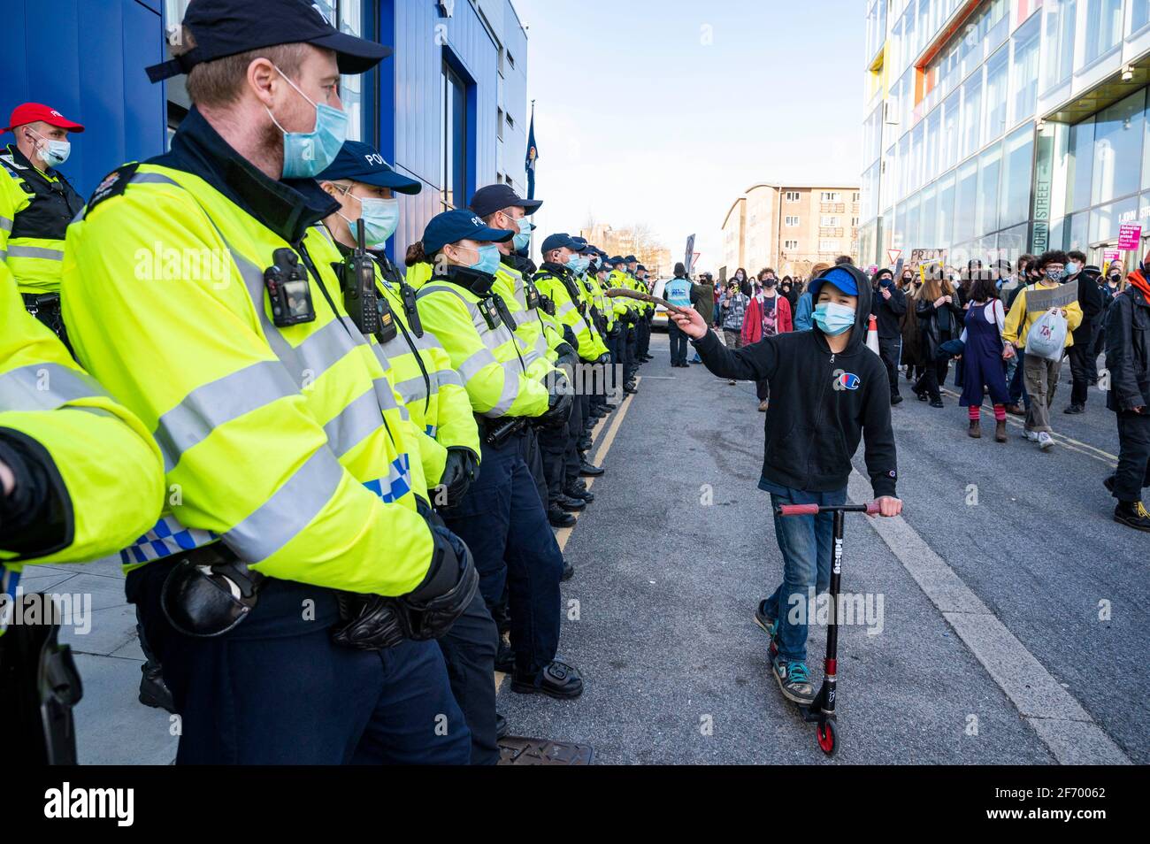 Brighton UK 3rd April 2021 - A youngster on a scooter passes by the police station as hundreds of "Kill The Bill" protesters march through Brighton in protest against the governments controversial new bill which would give police powers to crack down on peaceful protest : Credit Simon Dack / Alamy Live News Stock Photo