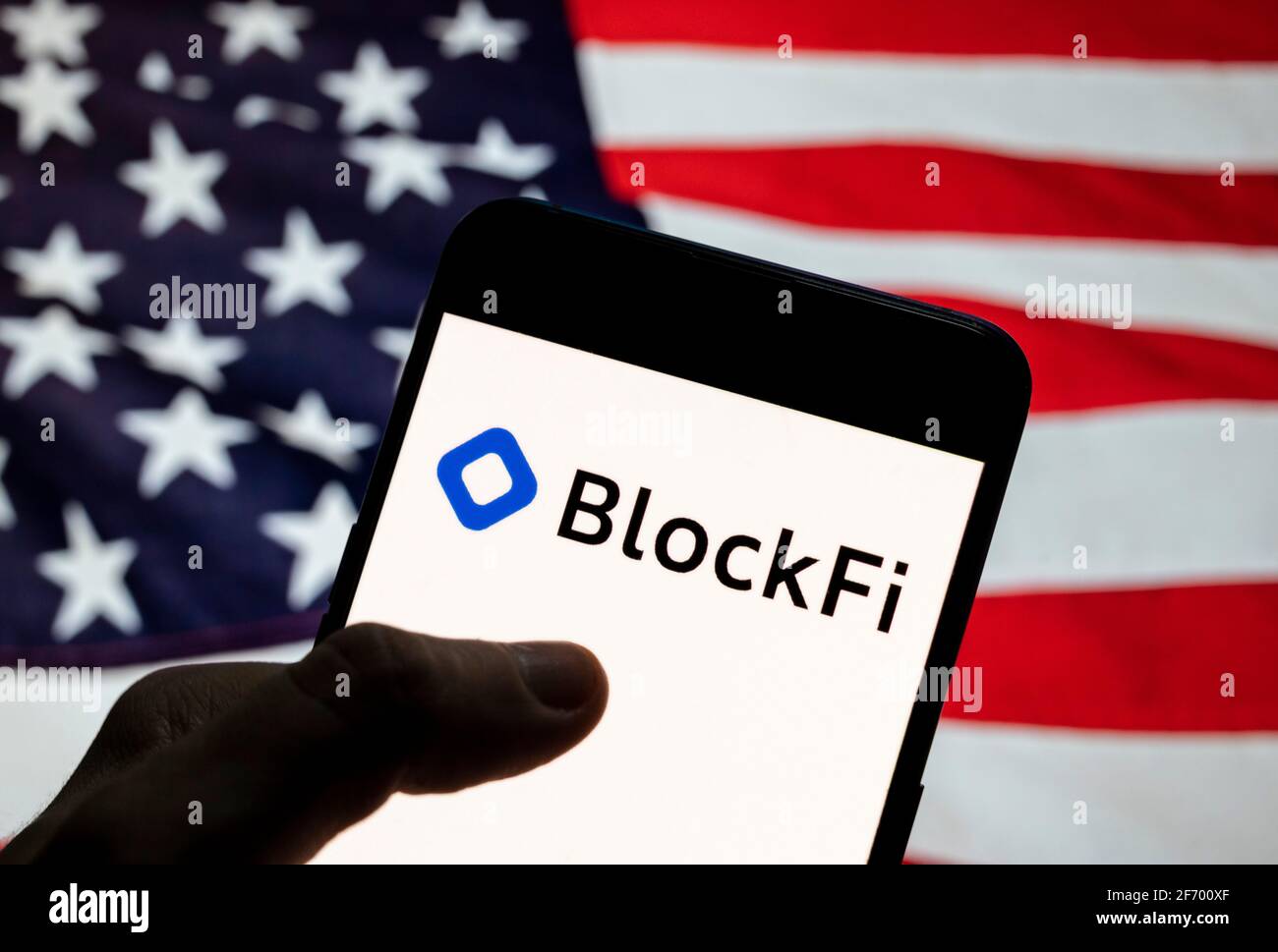 In this photo illustration the cryptocurrency exchange trading platform  Blockfi logo seen displayed on a smartphone with a flag of the United States  in the background Stock Photo - Alamy