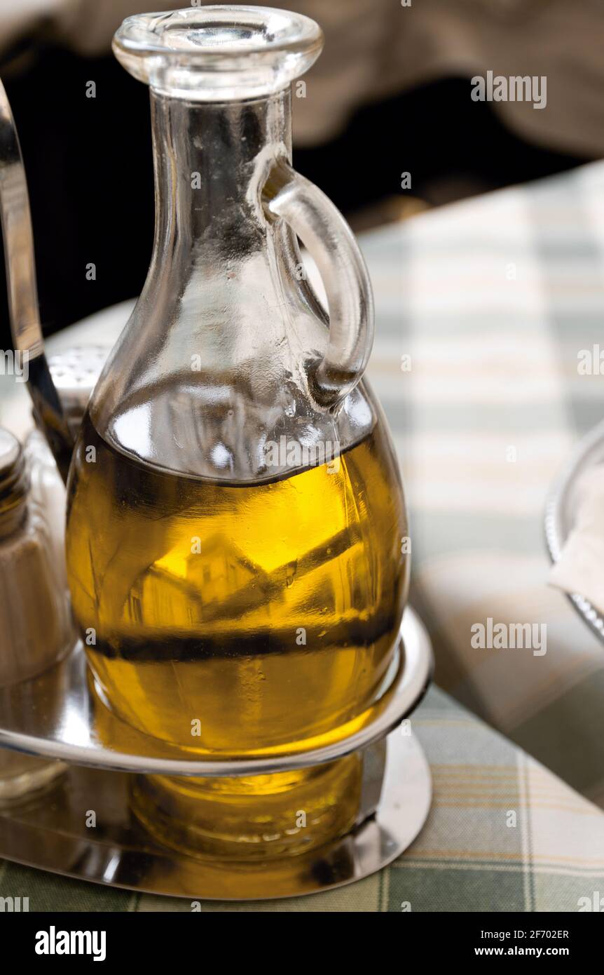 Detail of a glass jug with olive oil at a table Stock Photo