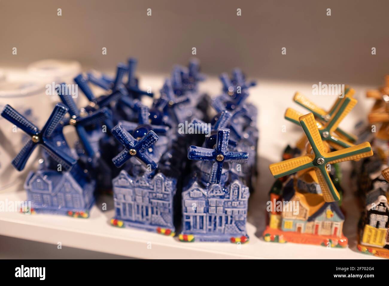 Small blue and yellow decorative ceramic windmills for sale on a shelf in a souvenir store in the Zaanse Schans in the Netherlands Stock Photo