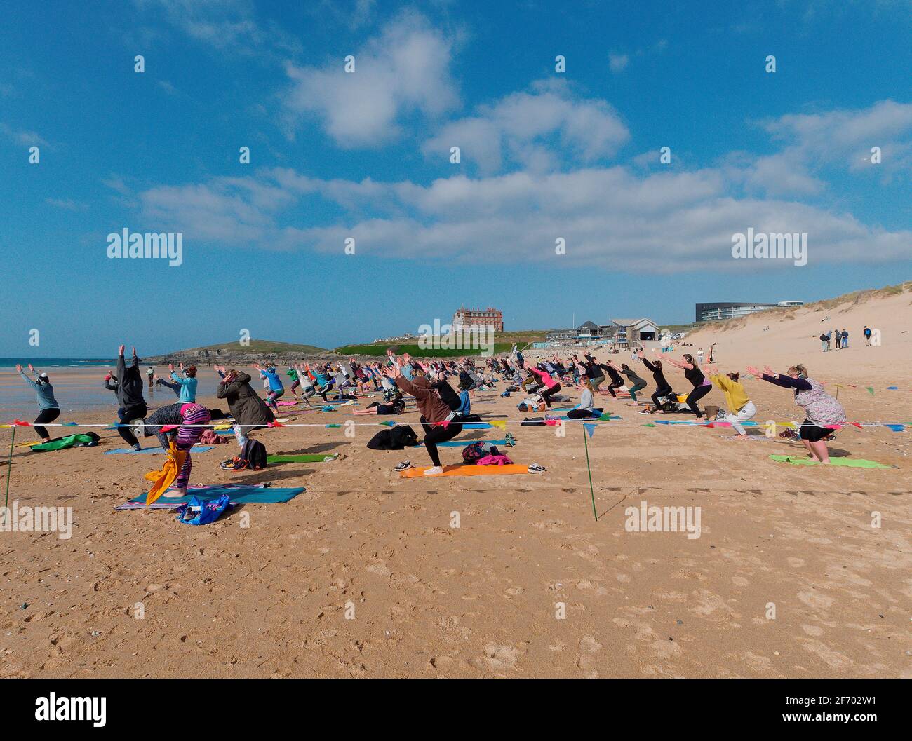 Newquay, Cornwall, England, 3rd  April 2021. UK weather: Cool with sunshine for a mass Yoga class involving 300 plus participants. Silent disco yoga organised by Anthony Durkin DJ in combination with Oceanflow yoga. Fistral beach. Credit: Robert Taylor/Alamy Live News� Stock Photo