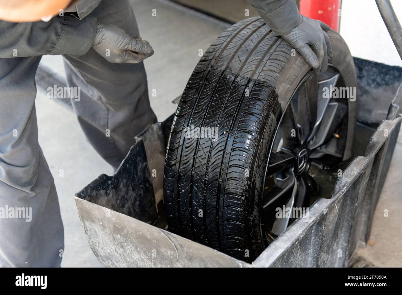 Gloved hands of mechanic performs leak detection on tire by dunking in