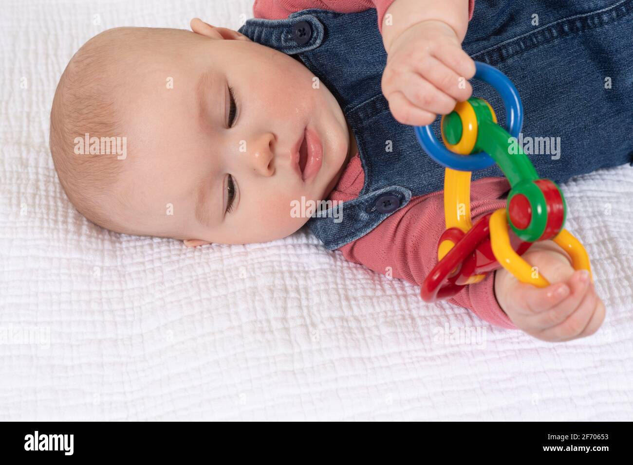4 month old baby girl, holding toy using both hands Stock Photo