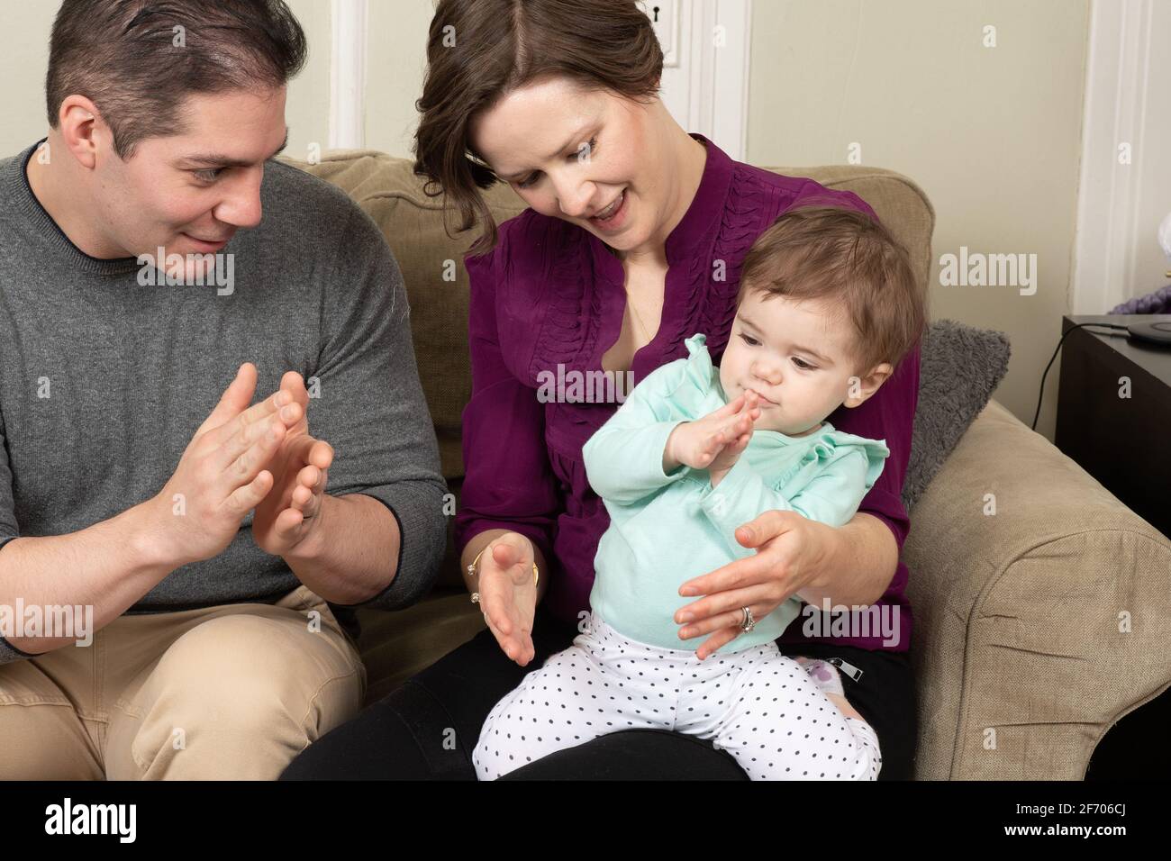 10 month old baby girl with parents playing clapping game Stock Photo