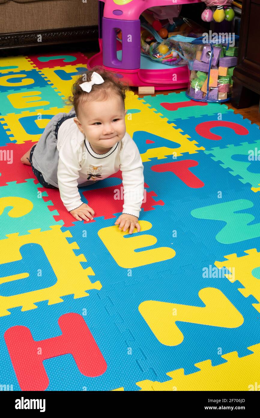 7 month old baby girl on floor, crawling, happy, bow in hair Stock Photo