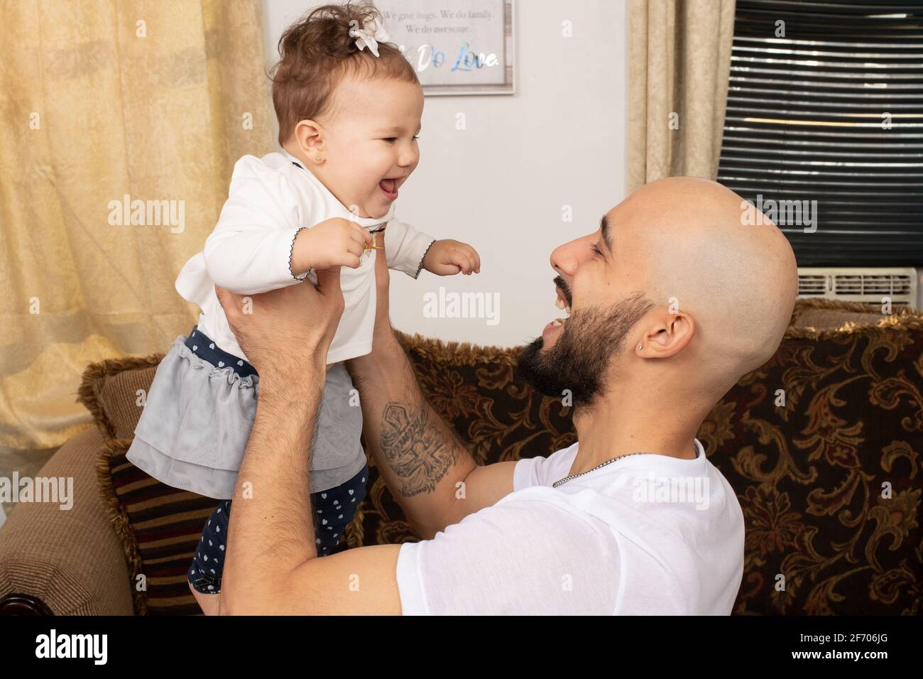 7 month old baby girl, interacting with father, held high Stock Photo