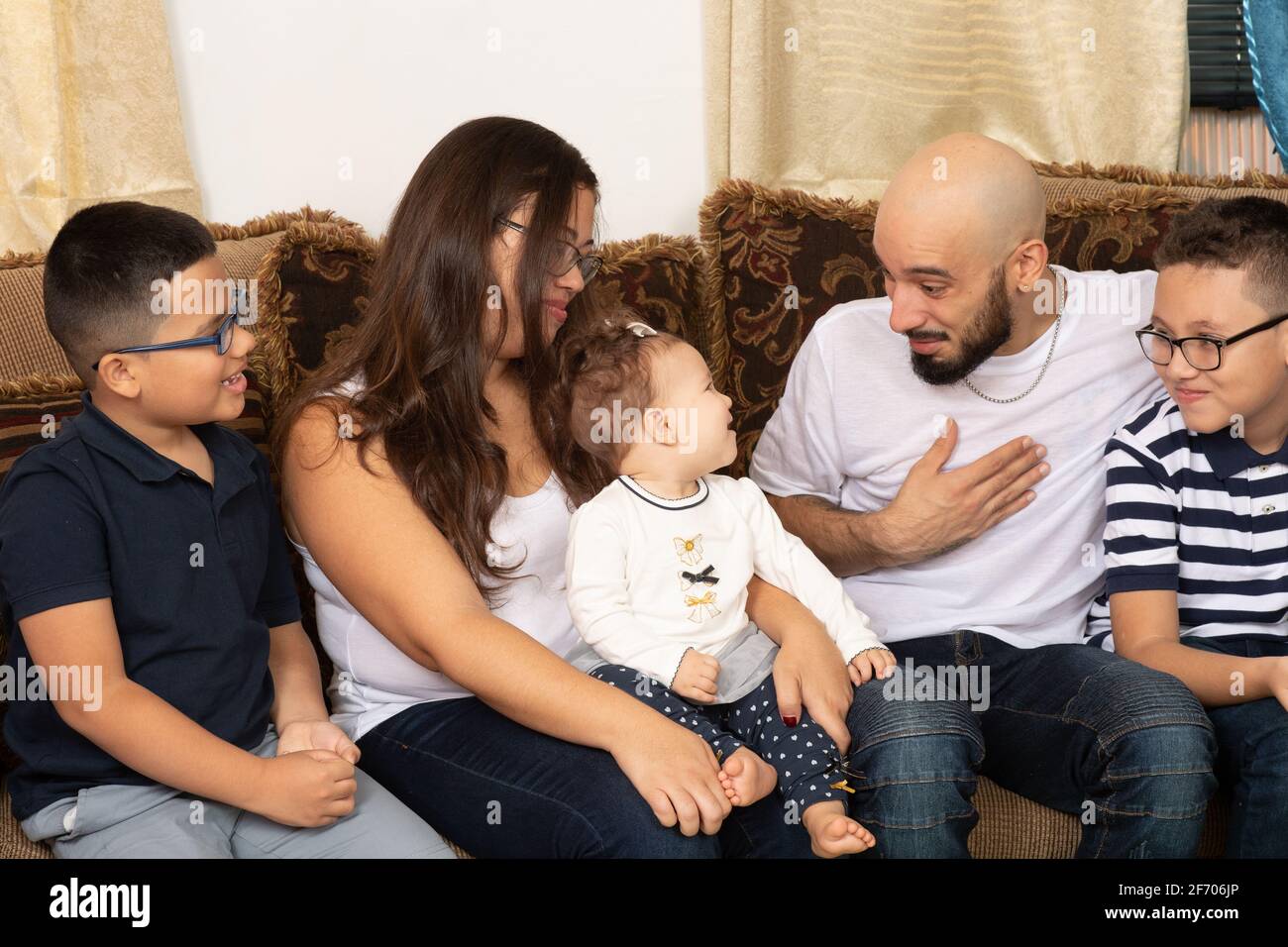Happy family portrait mother and father in their 30s, sons ages 9 and 7, and infant daughter, age 7 months, father interacting with baby girl, group Stock Photo
