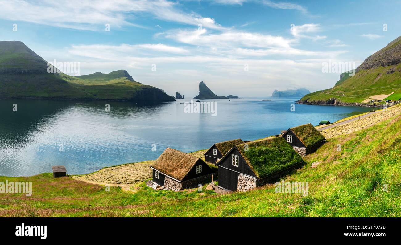 Picturesque view of tradicional faroese grass-covered houses in the village Bour. Drangarnir and Tindholmur sea stacks on background. Vagar island, Fa Stock Photo