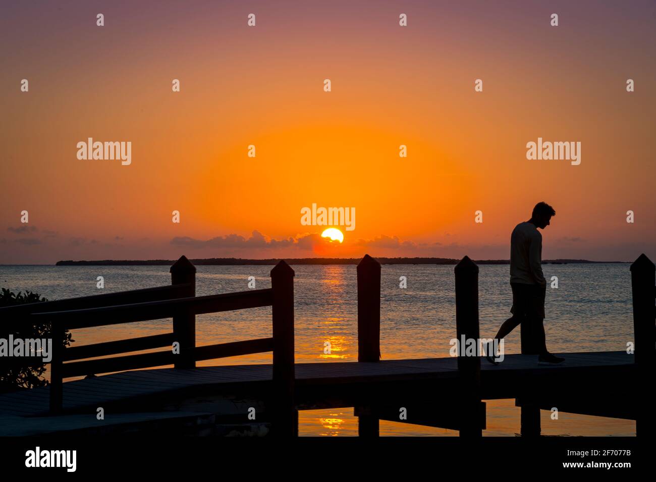 Sad man walking on pier at sunset, Key Largo Florida USA Stock Photo