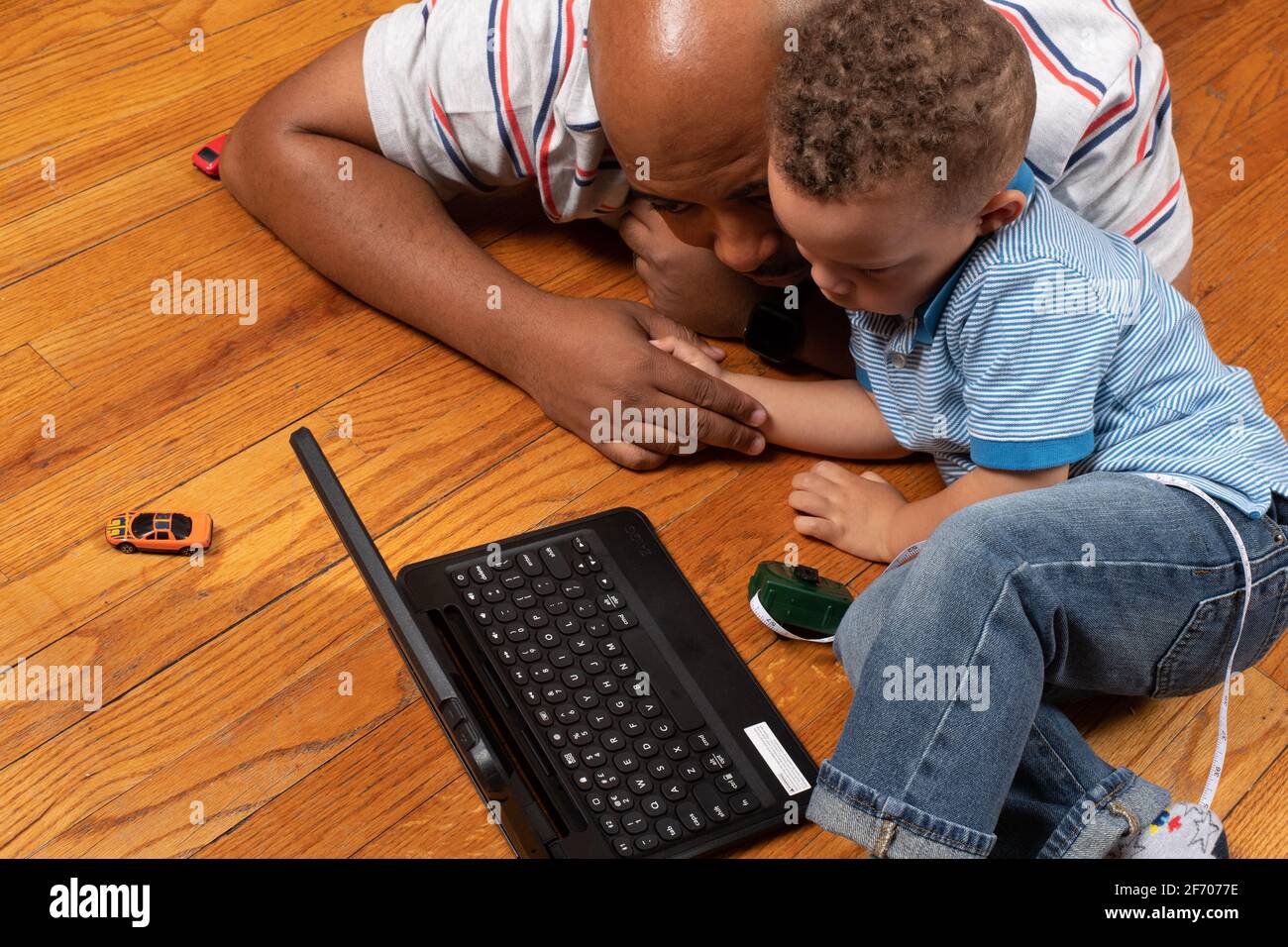 3 year old boy at home with father home learning using ipad provided by school district for at home learning during Covid-19 pandemic Stock Photo