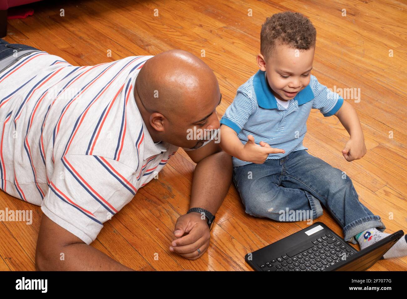 3 year old boy at home with father home learning using ipad provided by school district for at home learning during Covid-19 pandemic Stock Photo