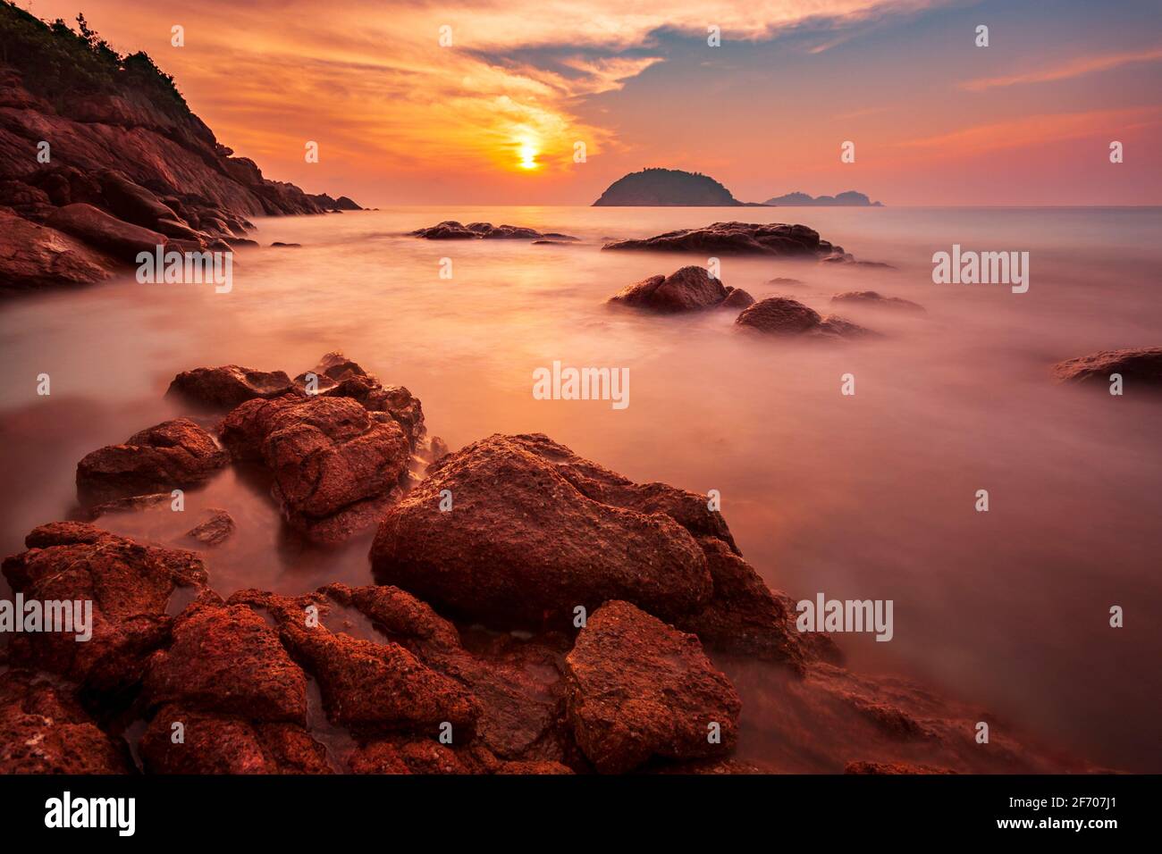 Long exposure of a warm sunset on the rocky beach of Redang Island, Malaysia Stock Photo