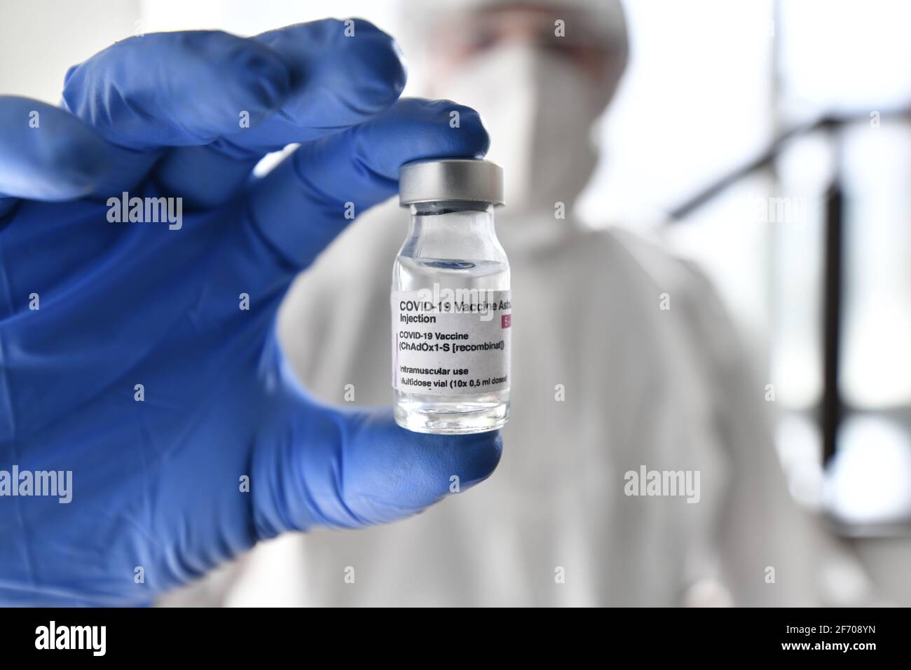 Nurse in ppe suit and gloves holds simulation Astra Zeneca  vaccine in front of the camera Stock Photo