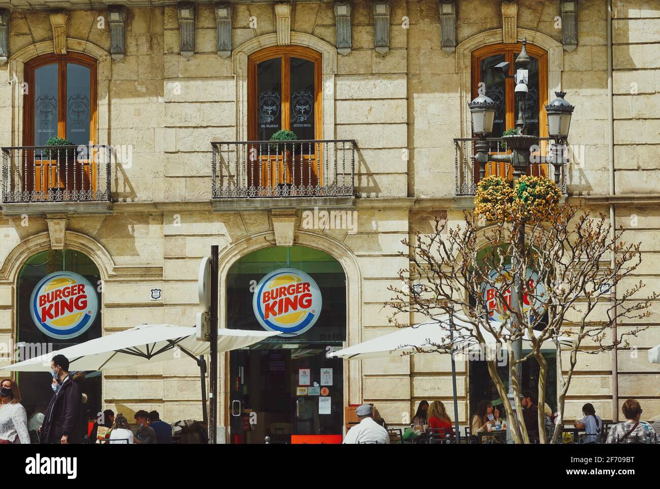 Burger King restaurant in a historic building in the center of Granada (Spain) with people eating at their outside tables, a sunny spring day Stock Photo