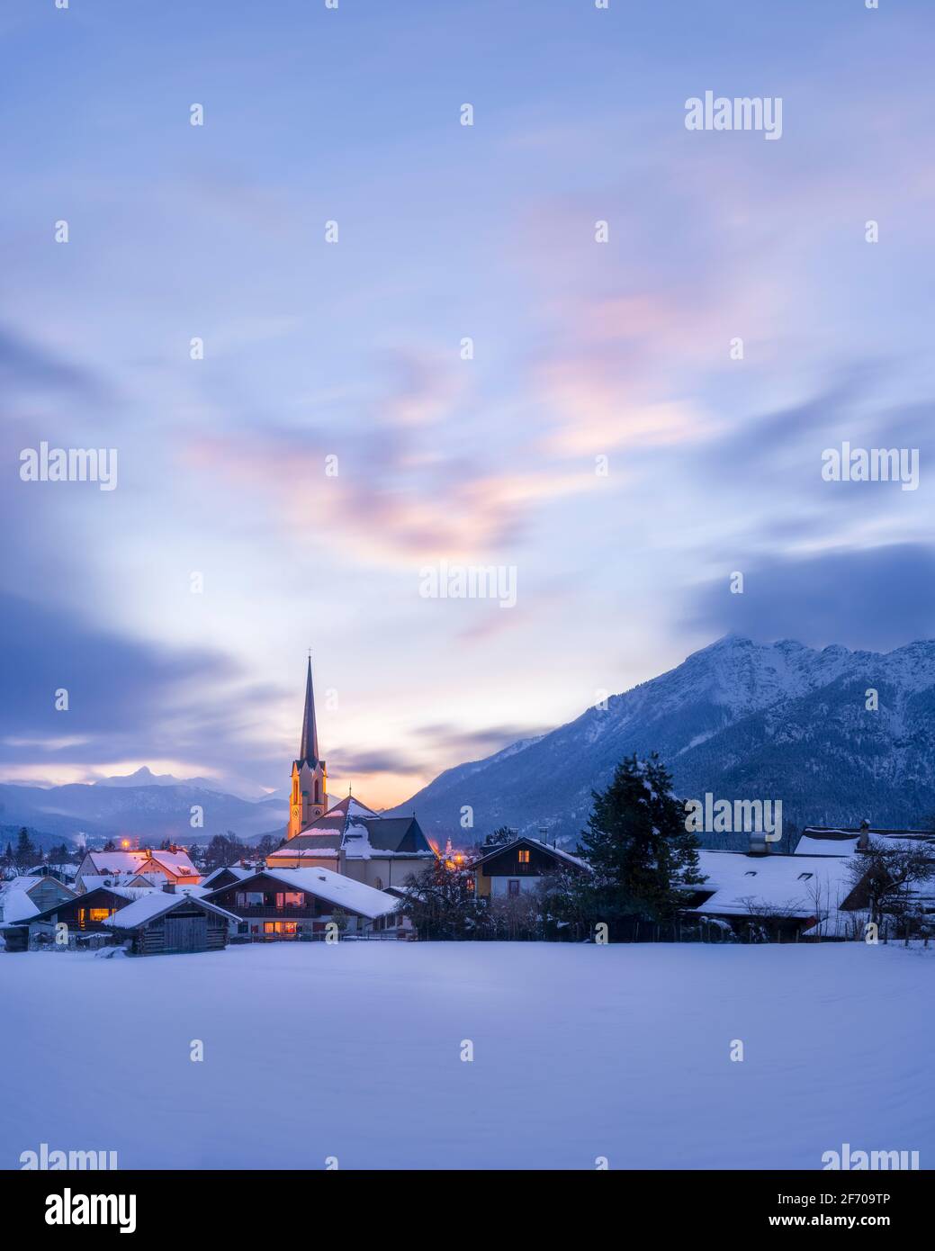 Beautiful winter cityscape with church tower illuminated at sunrise - Garmisch-Partenkirchen Stock Photo