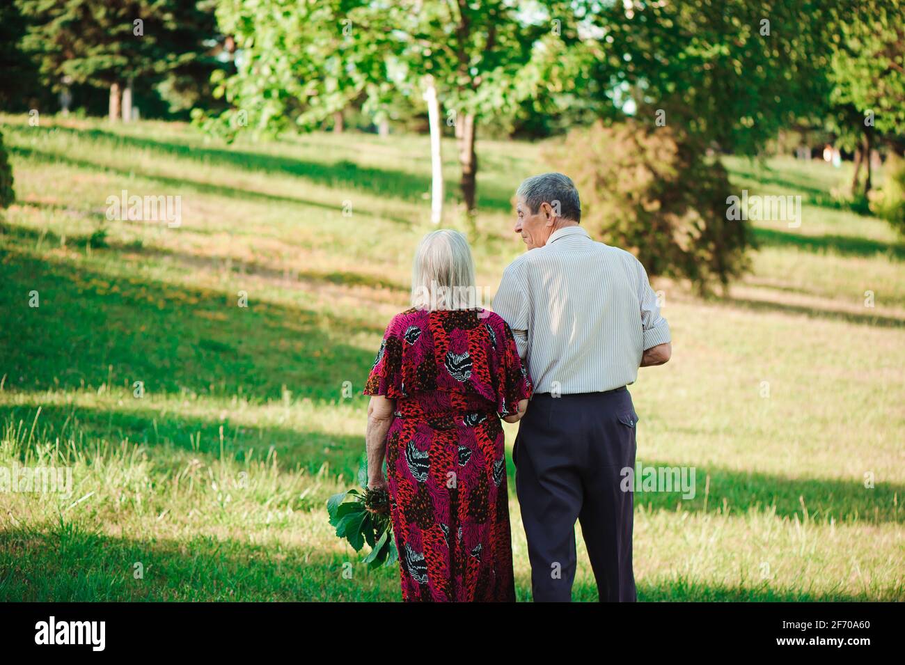 Age couple in love holding hands on a walk in the park in summer Stock ...