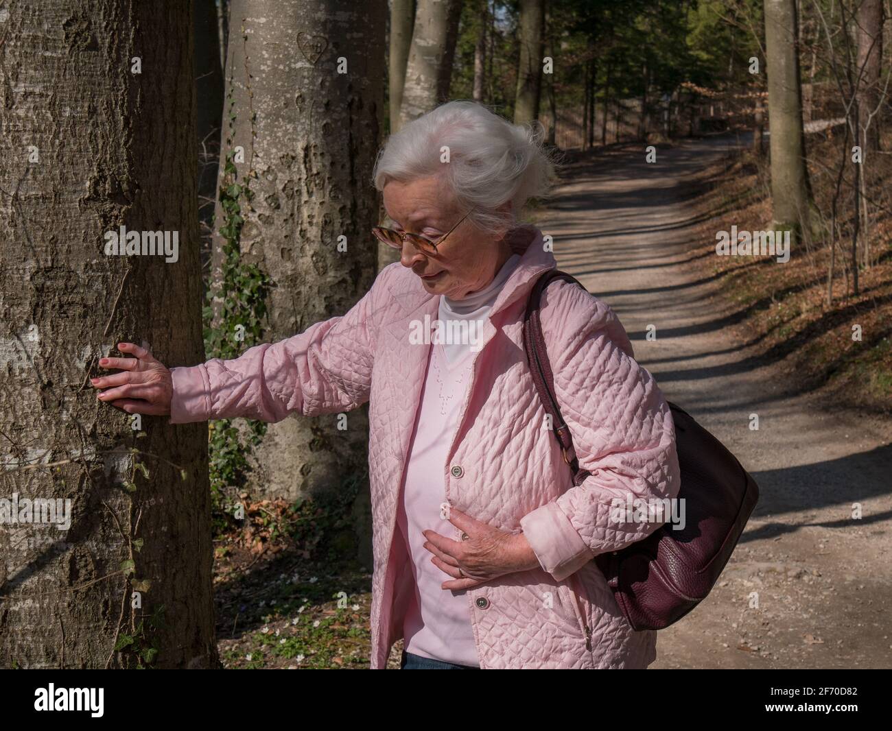 Senior woman has pain while walking in the park Stock Photo - Alamy