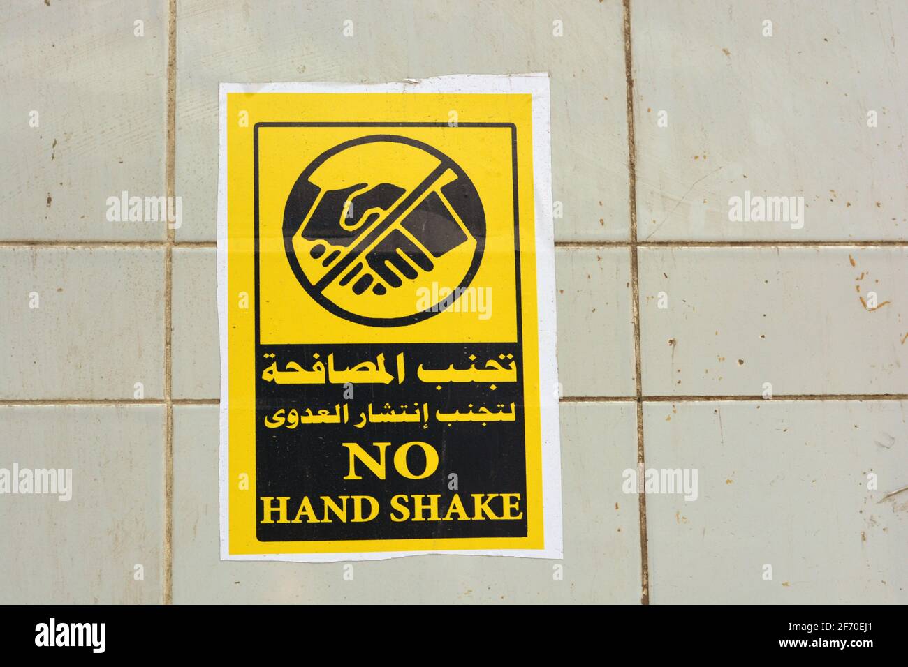 wall sticker in Arabic and English , translation of Arabic words (Avoid hand shake to prevent infection spread) , a wall sign to prevent corona virus Stock Photo