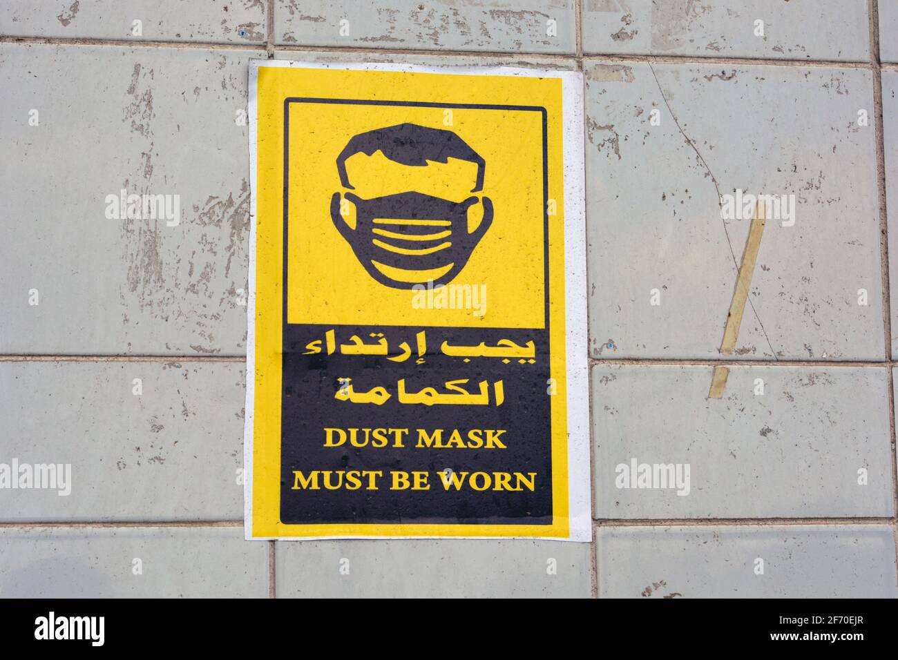 wall sticker in Arabic and English informs that face masks must be worn, the translation of Arabic words (face mask is a must) Stock Photo