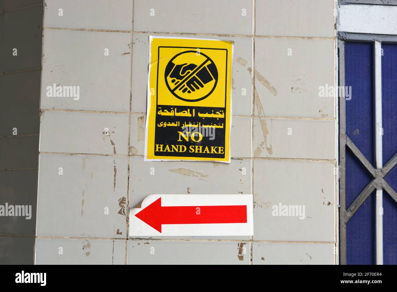 wall sticker in Arabic and English , translation of Arabic words (Avoid hand shake to prevent infection spread) , a wall sign to prevent corona virus Stock Photo