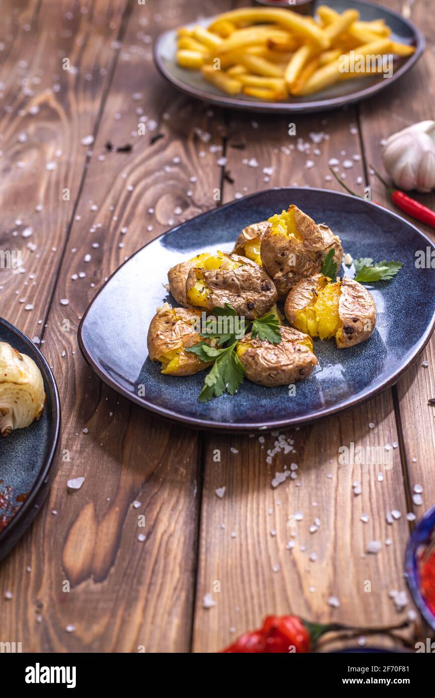 Potatoes in the skin, boiled, seasoned with herbs on a brown wooden background. Restaurant menu. Stock Photo
