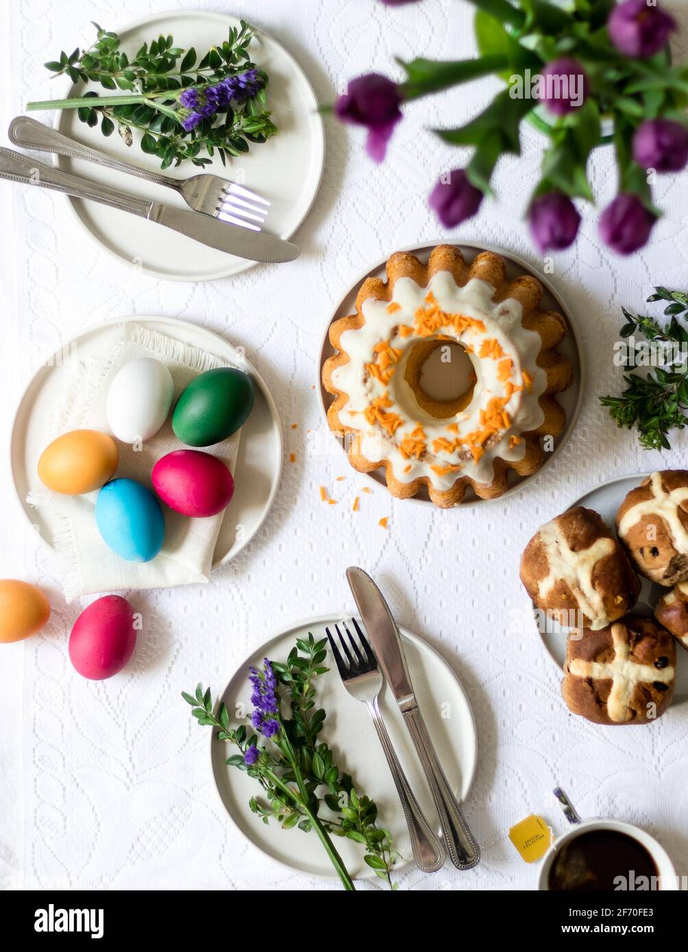 Easter morning breakfast scene - kitchen table with hand painted easter eggs, traditional Easter babka, hot cross buns, freshly made tea, tulilps. Stock Photo