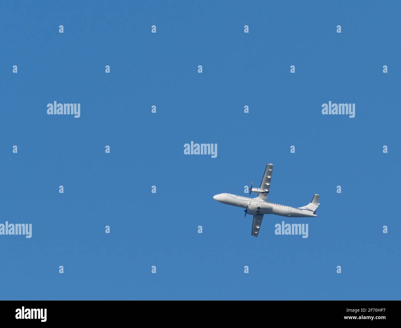 a white propeller plane flies in the blue sky Stock Photo - Alamy