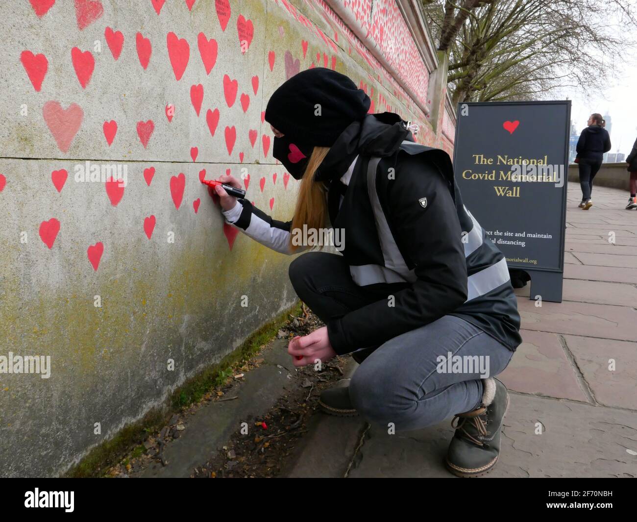 ‘An outpouring of love’ – enormous Covid-19 Memorial Wall begun opposite Parliament London, Monday 29 March– Bereaved families have today begun the creation of a vastCovid-19 Memorial Wall, on the Embankment opposite the Houses of Parliament in Westminster, London.Painting individual red hearts for each of the more than 145,000 lives lost to the virus, the group hopes to put personal stories at the heart of the Government’s approach to learning lessons from  the pandemic and expects the wall to stretch to  over half a kilometre in the coming days. Stock Photo