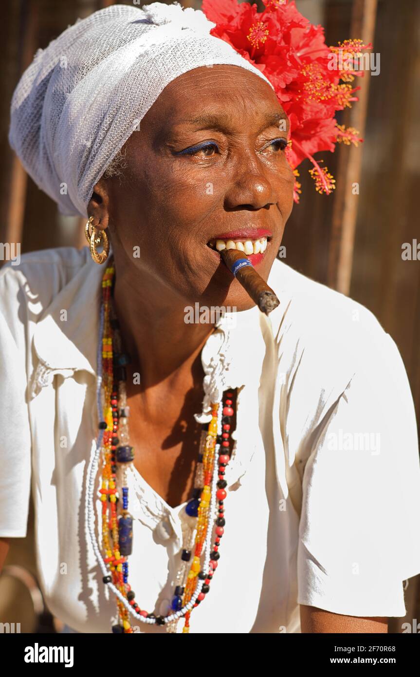 Cigar smoking Cuban woman in white attire typical of those that follow the religion of Santeria. Havana. Habana, Cuba Stock Photo