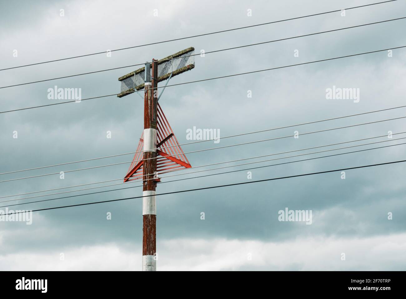 a red triangle mounted on a post, serving as a visual warning marker to pilots of approaching aircraft to the presence of power lines Stock Photo