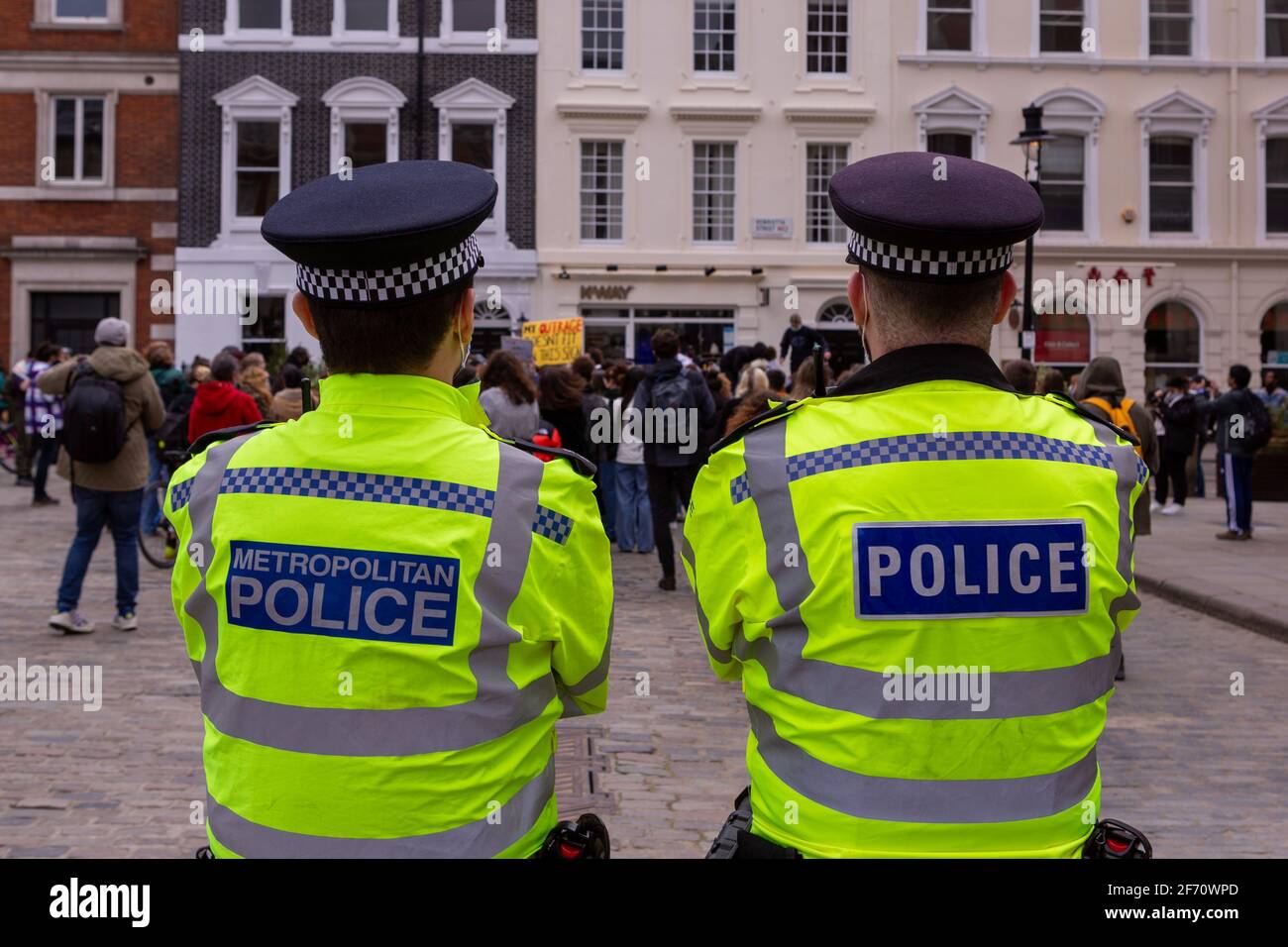 Police officers looking at protesters during the demonstration.A Month after kidnap and murder of 33-year-old Sarah Everard, women's rights protesters marched in central London chanting slogans and protested what they said had been a lack of action by government and police services. Sarah Everard disappeared on March 3rd and her body was found on March 12th. Stock Photo