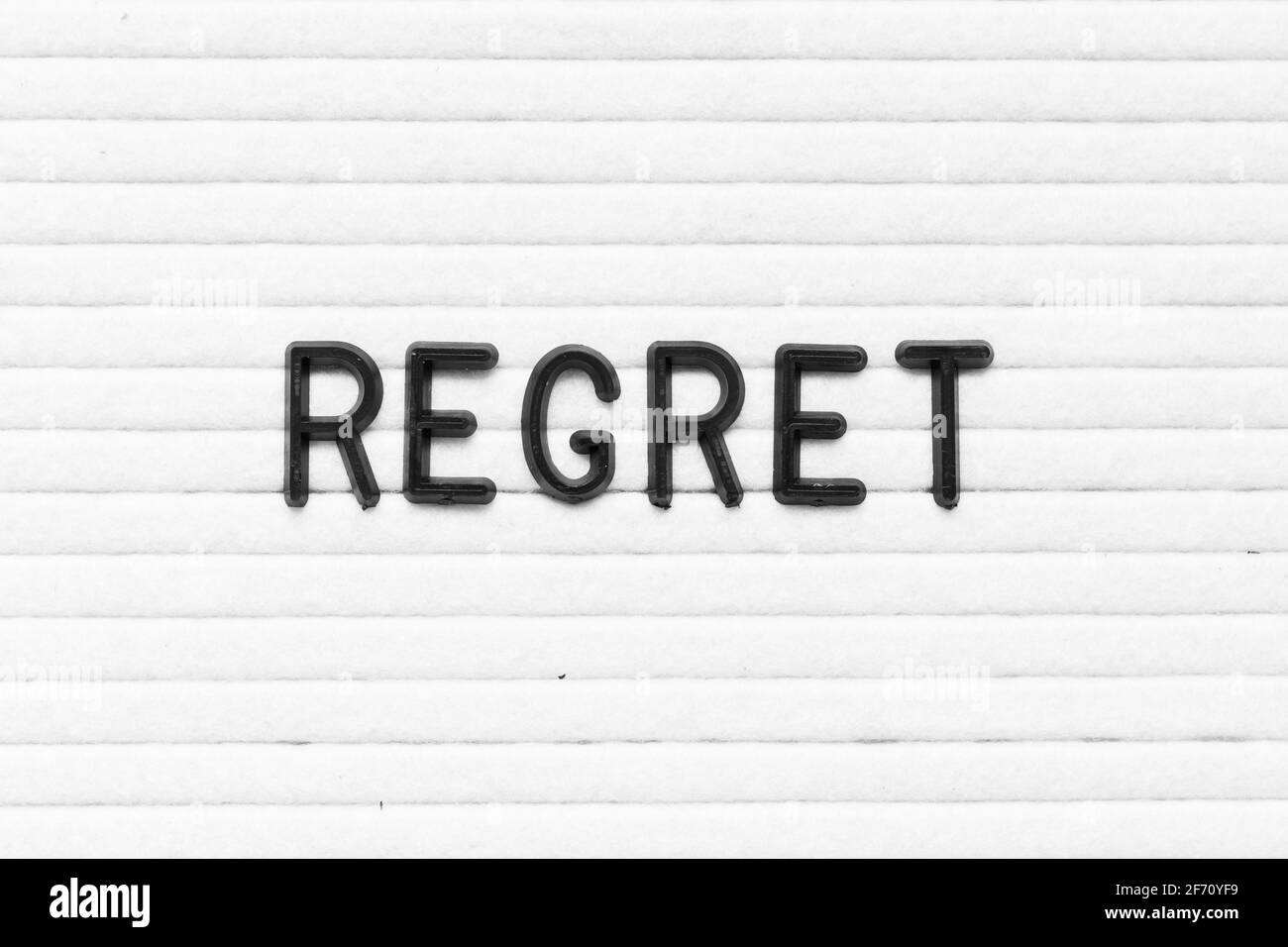 Black color letter in word regret on white felt board background Stock Photo
