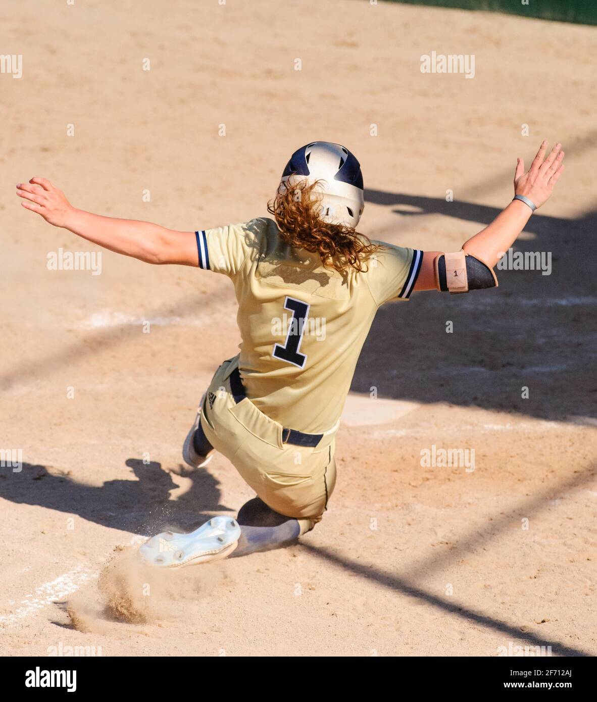 A Female Baseball Player Is Sliding Into Home Plate In Vertical Image Format Stock Photo