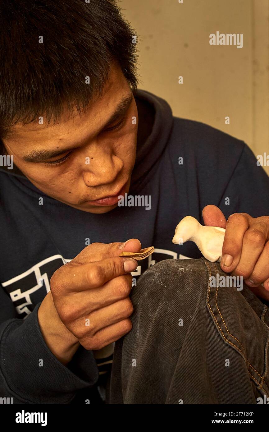 Inuit artist up close doing fine detailing of the narwhal whale art Stock Photo
