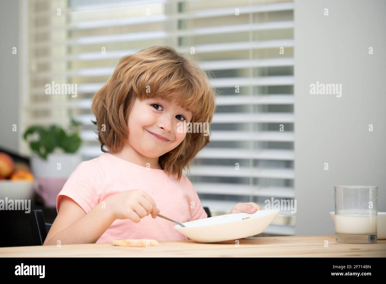 Child eat. Little healthy hungry boy eating soup with spoon. Stock Photo