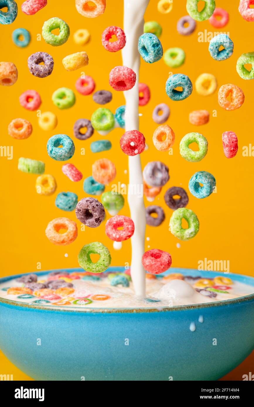 Dropping cereals and pouring milk into a blue bowl, isolated on an